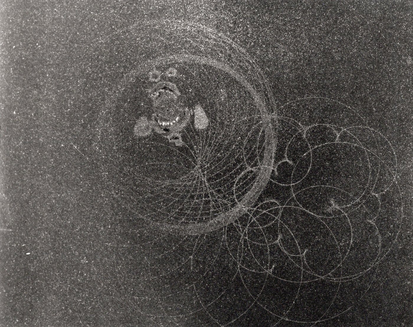 Birth of Ego - detail, 1992 - a dense dark granular field crossed by fine overlapping compass arcs, with a small cluster of forms near the top.