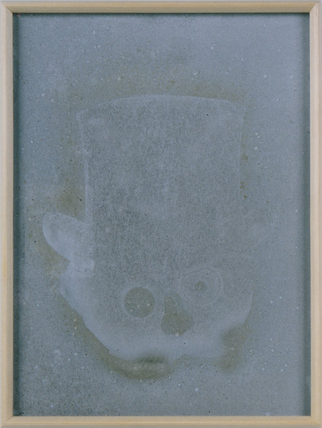 Dicey, 1990 - a skull-like form almost dissolved into a blue-grey dust field, barely legible inside a plain frame.