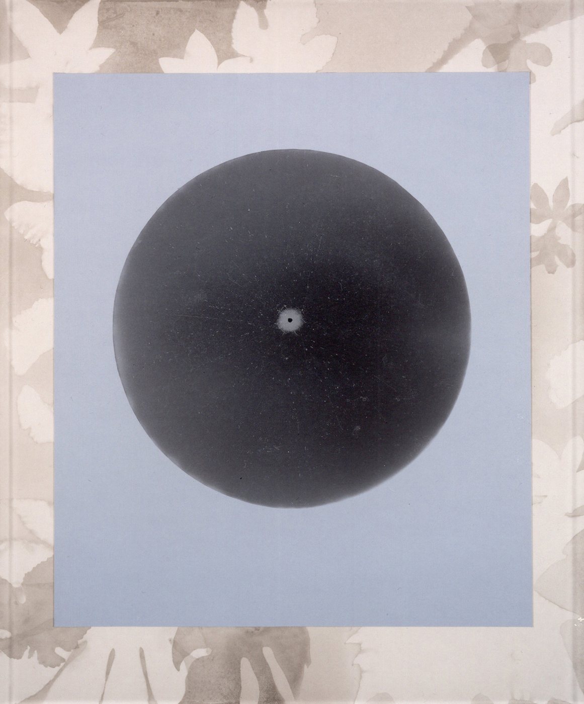 &Eacute;&eacute;n Waterdruppel, 1990 - a near-black sphere with a single bright point at its centre, on a pale blue-grey ground inside a faint floral border.