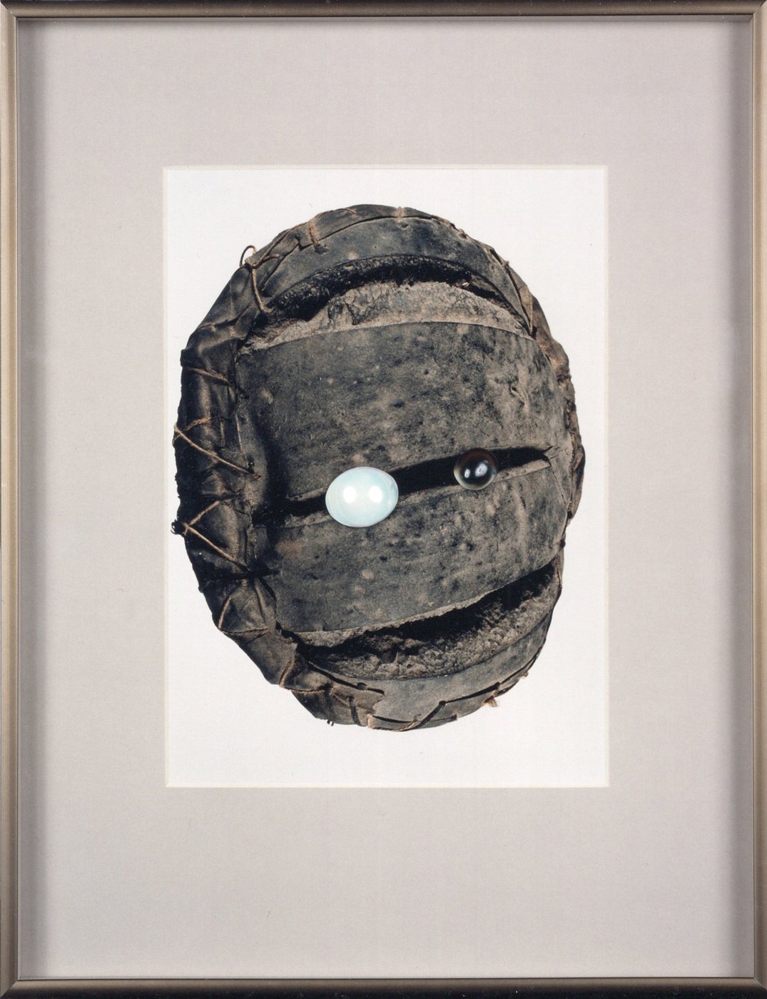 Zwartbrood (The Favourite), 1987 - a dark round bread-like form bound with cord, a single pale stone set into it like an eye, mounted and framed.